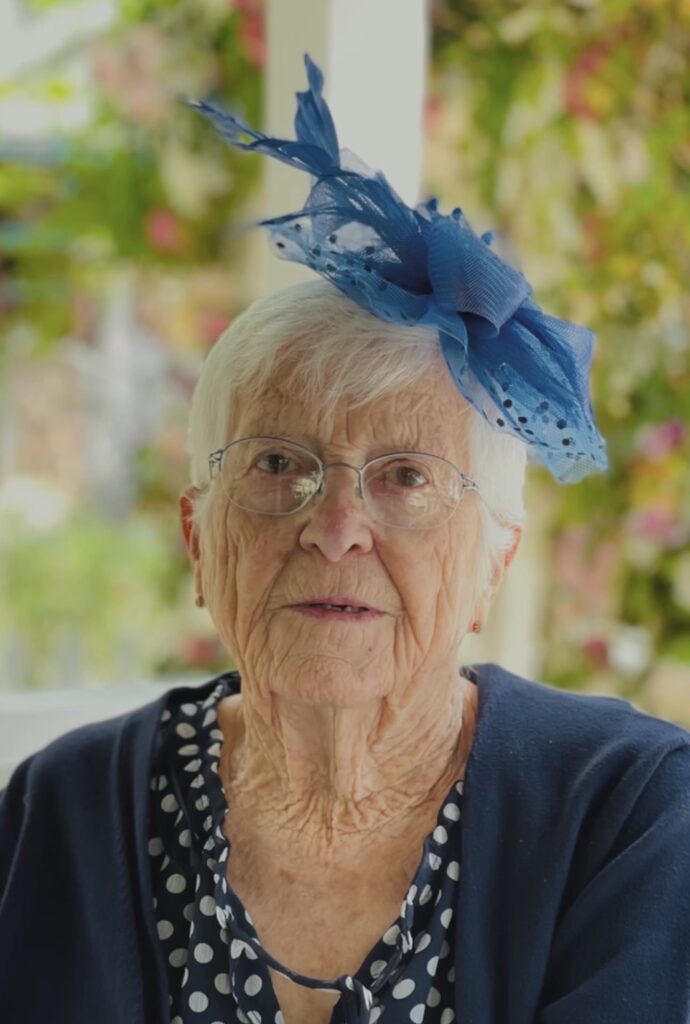 Older woman wearing a blue feather head piece