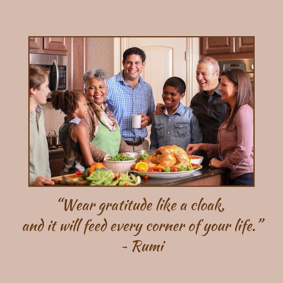 A group of people stand over a Thanksgiving feast. The group is diverse with both children and adults.