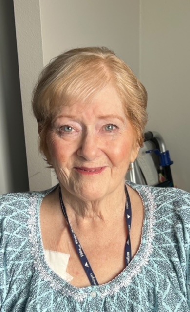 Blonde woman with blue shirt and necklace