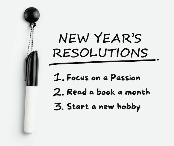 A list of New Year's Resolutions written on a white board with a sharpie hanging on a peg.