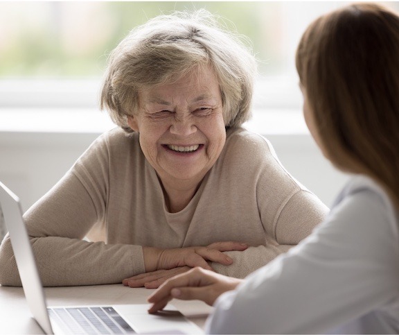 An older lady speaking with a younger woman at a computer.