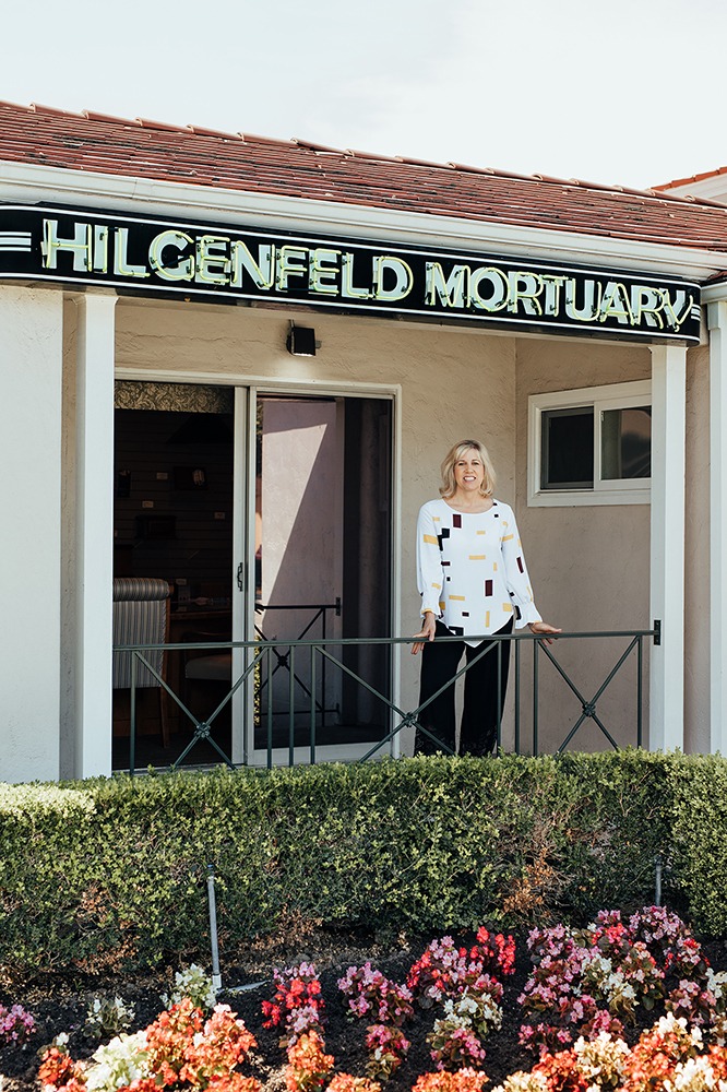 welcome_img Woman stands under neon Hilgenfeld Mortuary sign